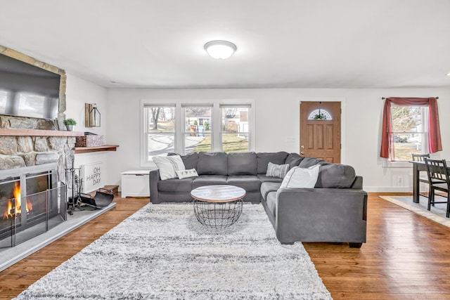 living area with a fireplace, baseboards, and wood finished floors