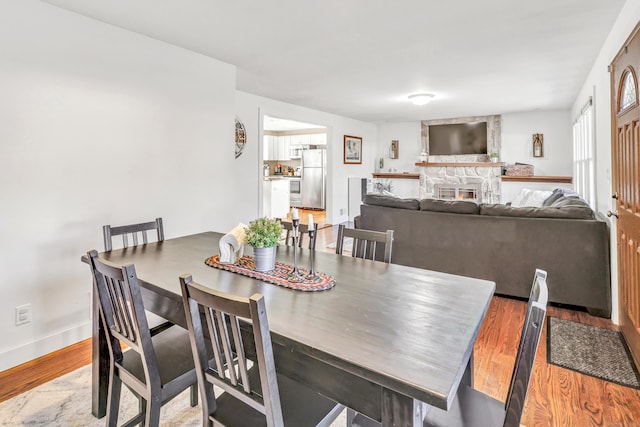 dining room featuring baseboards, wood finished floors, and a fireplace