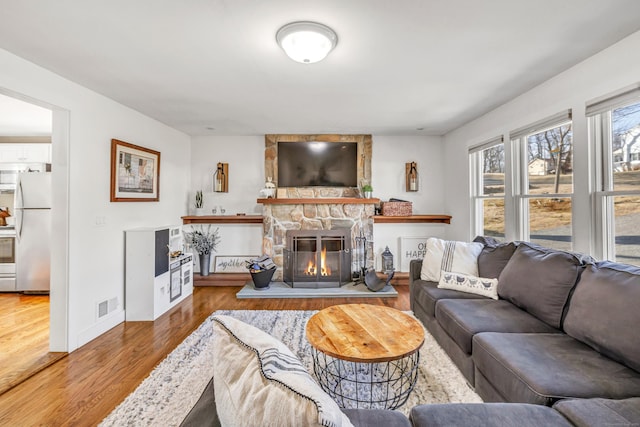 living room with visible vents, baseboards, wood finished floors, and a fireplace