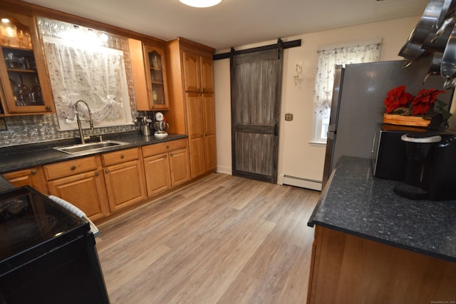 kitchen with a sink, a baseboard radiator, light wood-style flooring, and brown cabinetry