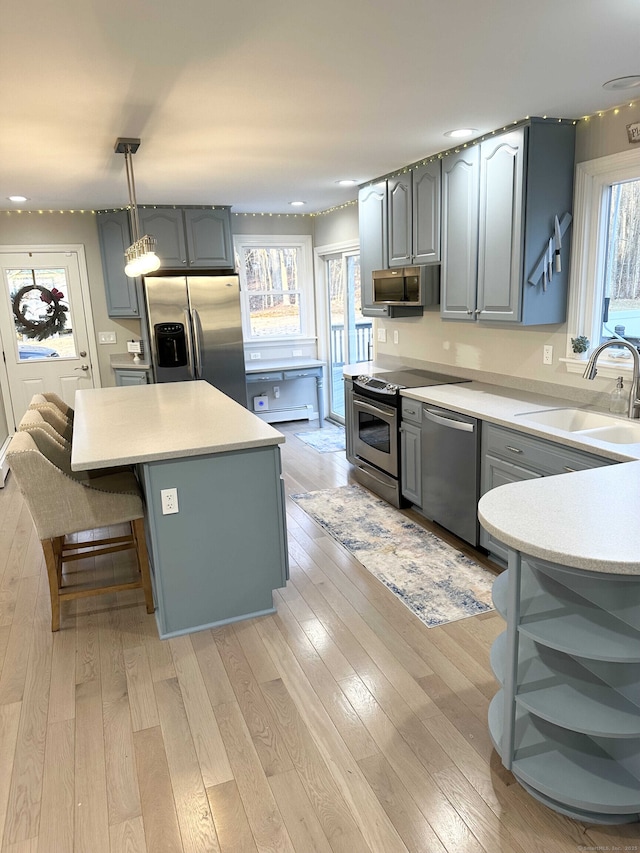 kitchen featuring open shelves, gray cabinets, appliances with stainless steel finishes, and a sink