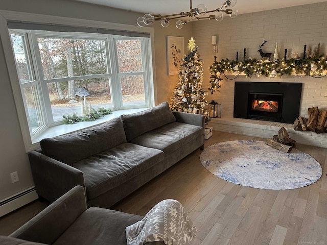 living room featuring baseboard heating, a fireplace, and wood finished floors