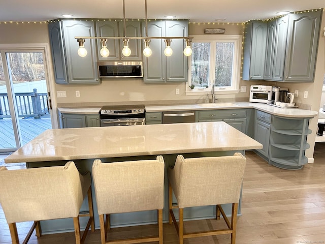 kitchen with a sink, gray cabinets, light wood-style flooring, stainless steel appliances, and open shelves