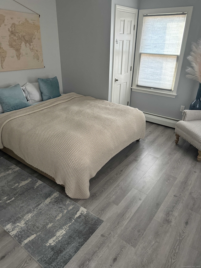 bedroom featuring wood finished floors and a baseboard radiator