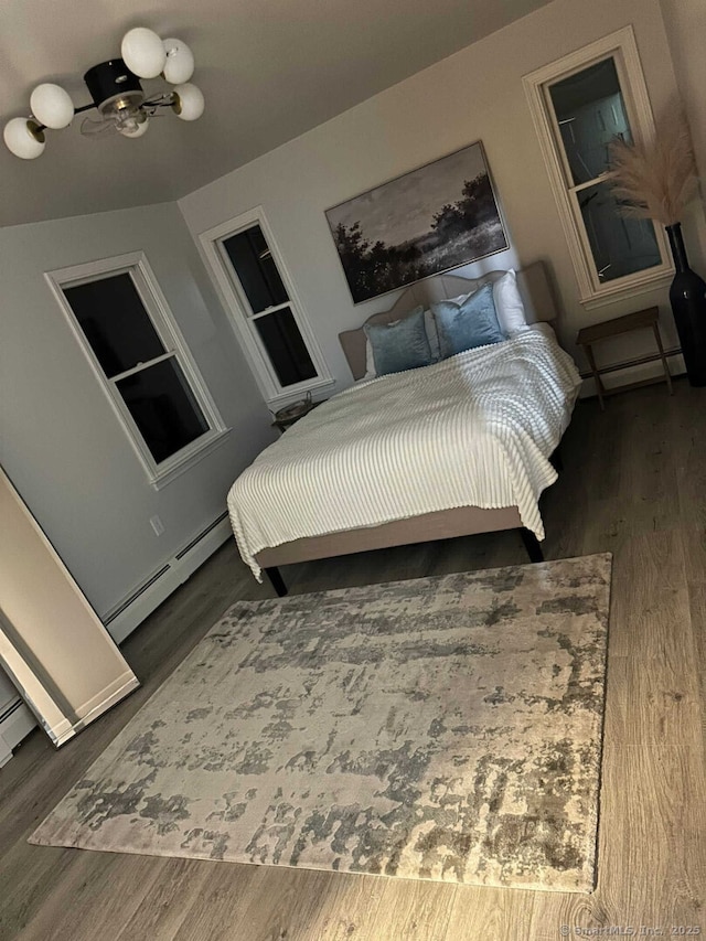 bedroom with a baseboard heating unit, wood finished floors, and a baseboard radiator