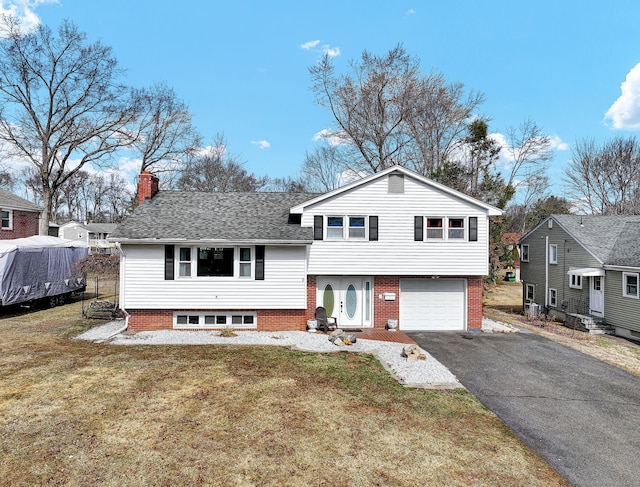 tri-level home with a front yard, a shingled roof, a chimney, a garage, and aphalt driveway