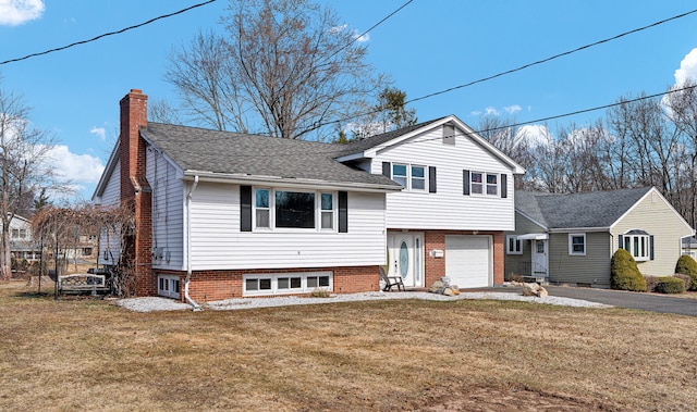 split level home with a front lawn, entry steps, a chimney, driveway, and an attached garage