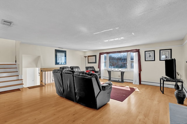 living area with visible vents, a textured ceiling, and wood finished floors