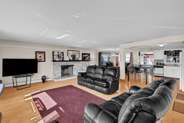 living area featuring a stone fireplace, light wood-style flooring, a textured ceiling, and baseboard heating