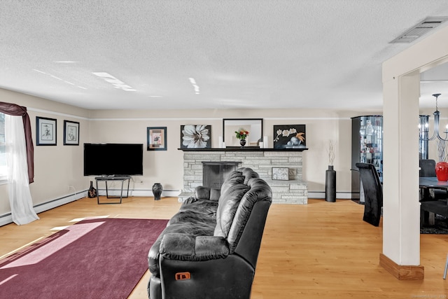 living area featuring visible vents, a textured ceiling, a stone fireplace, and wood finished floors