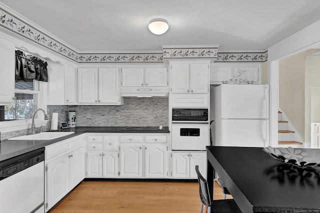 kitchen with under cabinet range hood, white cabinets, white appliances, and a sink