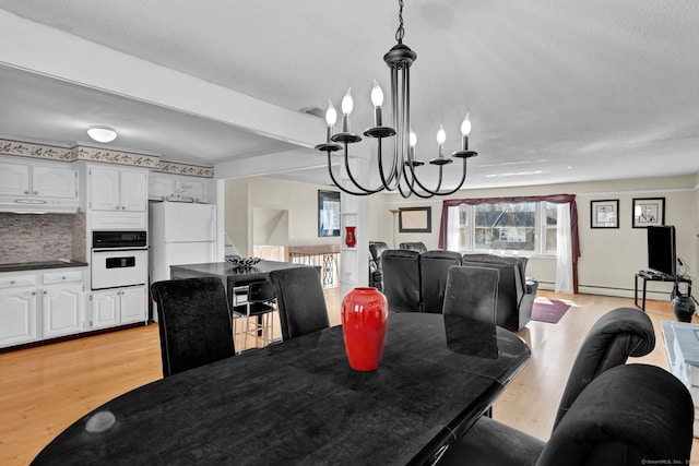 dining space featuring light wood-style floors, a notable chandelier, and a baseboard heating unit