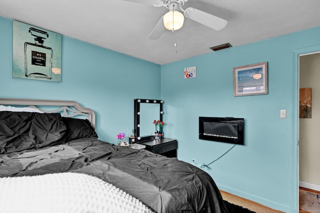 bedroom featuring visible vents, baseboards, wood finished floors, and a ceiling fan