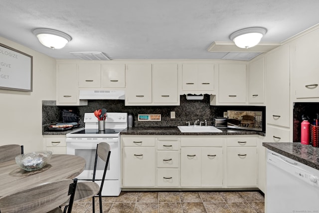 kitchen featuring under cabinet range hood, white appliances, dark countertops, and a sink