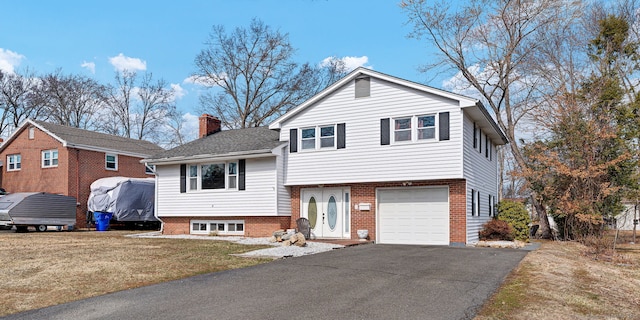 split level home featuring a front lawn, aphalt driveway, a garage, brick siding, and a chimney