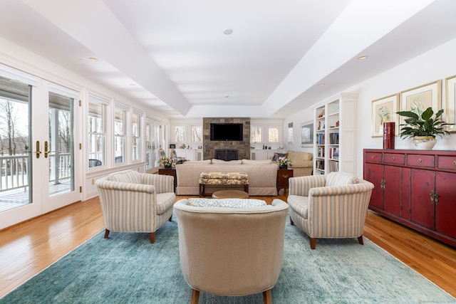 living area with a wealth of natural light, a raised ceiling, and wood finished floors