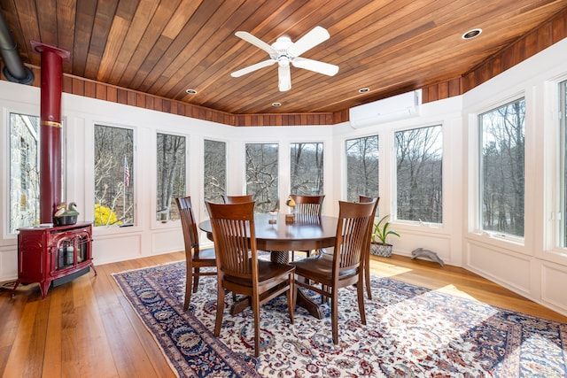 sunroom featuring wooden ceiling, a wall mounted AC, a wood stove, and a ceiling fan