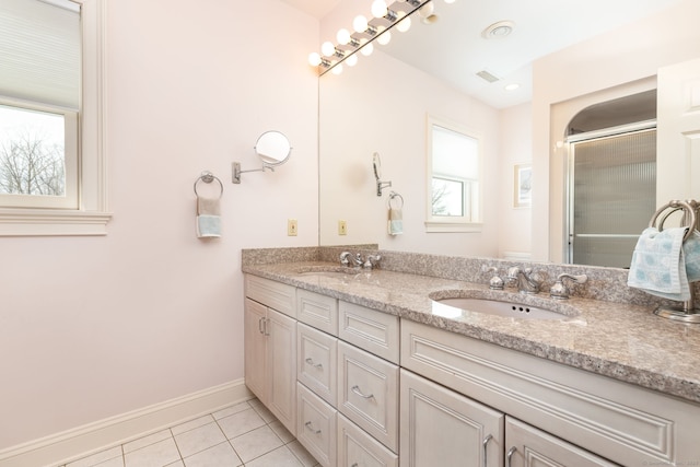 full bath with a sink, visible vents, double vanity, and tile patterned floors