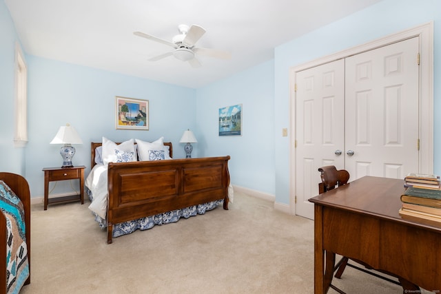 bedroom featuring a closet, baseboards, light colored carpet, and a ceiling fan