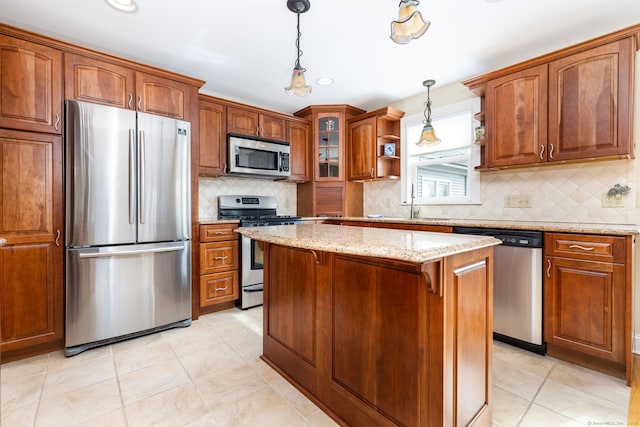 kitchen with brown cabinetry, decorative light fixtures, stainless steel appliances, and light stone countertops