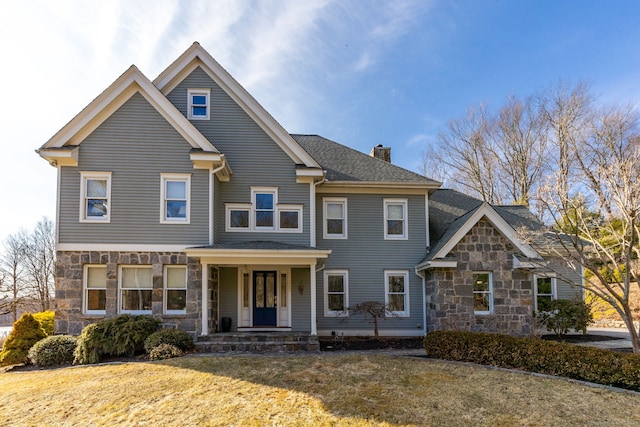 view of front of property with a front yard, stone siding, and a chimney