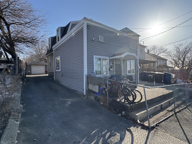 view of front facade with a detached garage, an outbuilding, fence private yard, and driveway