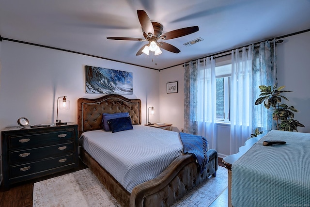 bedroom with ceiling fan, visible vents, and wood finished floors