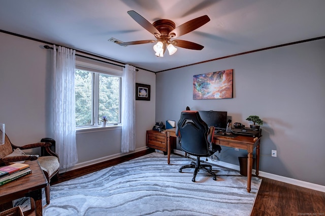 office area featuring wood finished floors, visible vents, baseboards, ornamental molding, and ceiling fan