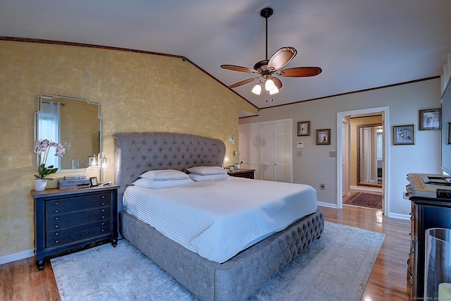 bedroom with lofted ceiling, crown molding, wood finished floors, and baseboards