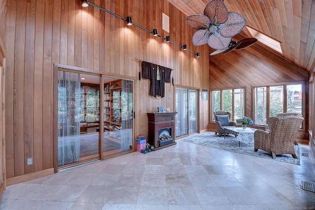 unfurnished living room with wooden walls, wood ceiling, high vaulted ceiling, and ceiling fan