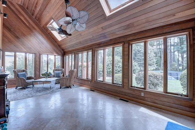 unfurnished sunroom featuring lofted ceiling with skylight, visible vents, wood ceiling, and a ceiling fan