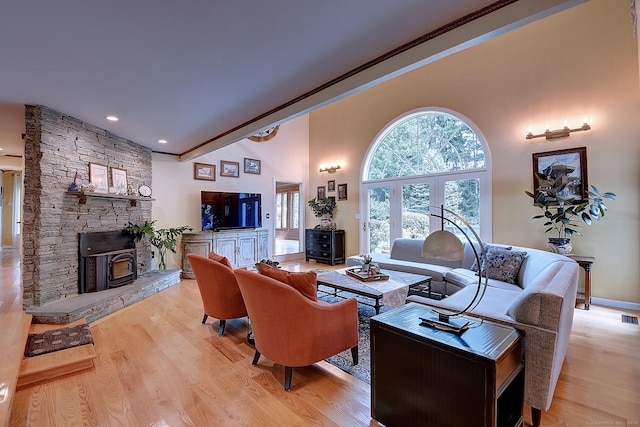 living area with visible vents, light wood-style flooring, a fireplace, and a towering ceiling