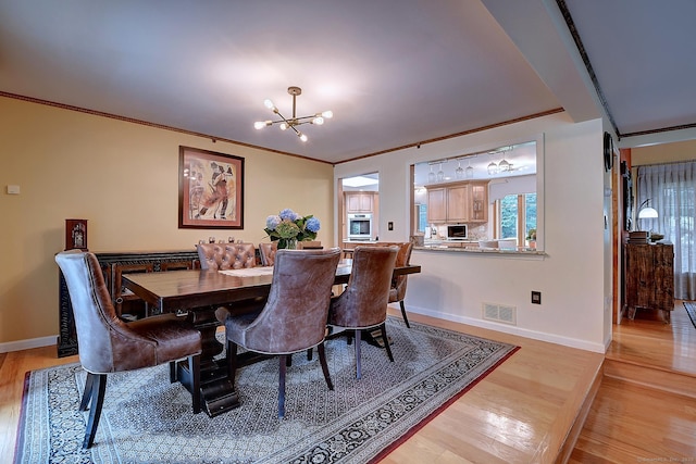 dining space with a notable chandelier, visible vents, light wood-style floors, and ornamental molding