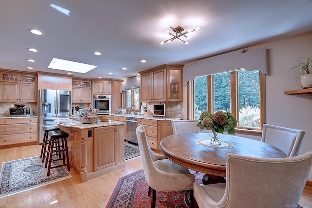 dining area with recessed lighting, plenty of natural light, light wood-style flooring, and a skylight