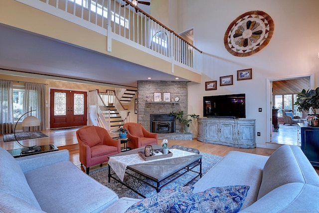 living area with stairway, a high ceiling, wood finished floors, and a fireplace