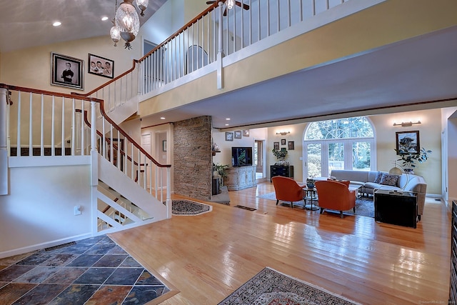 living area featuring stairway, wood finished floors, baseboards, and a towering ceiling