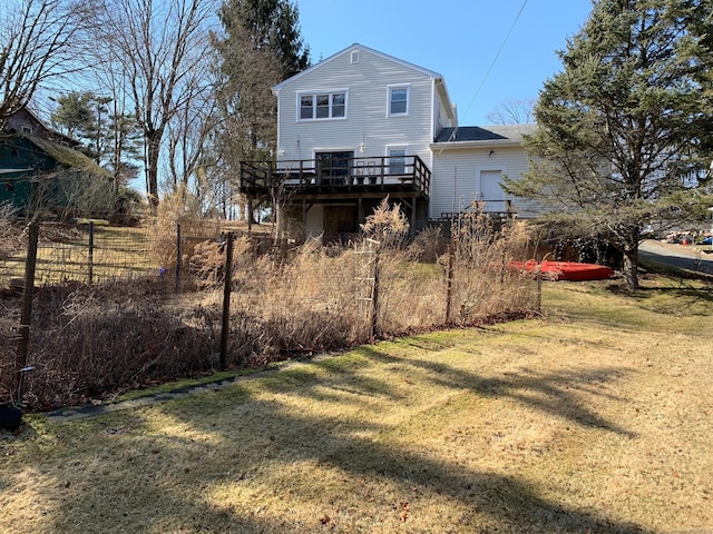 back of house featuring a lawn, a deck, and fence