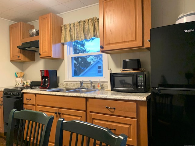 kitchen featuring black appliances, light countertops, under cabinet range hood, and a sink