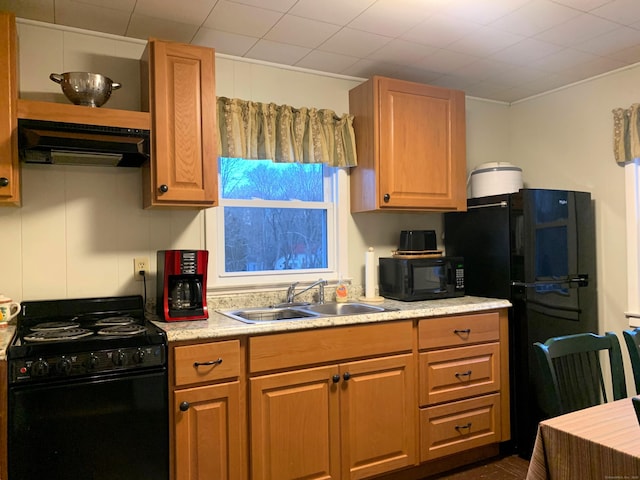 kitchen featuring black appliances, light countertops, under cabinet range hood, and a sink