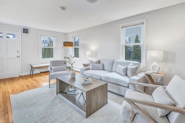 living area with baseboard heating, light wood-type flooring, and baseboards