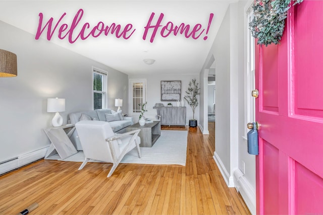 entryway featuring arched walkways, baseboards, and light wood-style floors