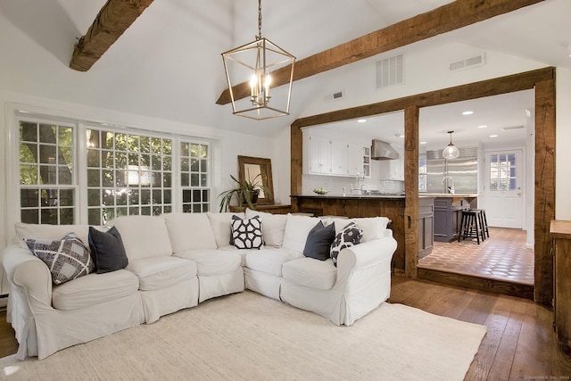 living area featuring visible vents, high vaulted ceiling, beam ceiling, wood-type flooring, and a notable chandelier