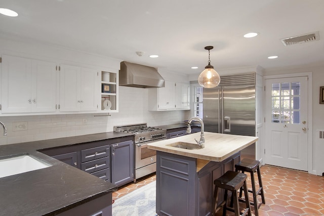 kitchen with visible vents, high quality appliances, wall chimney exhaust hood, and a sink