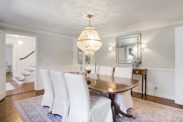 dining area with a chandelier, wood finished floors, stairs, and crown molding