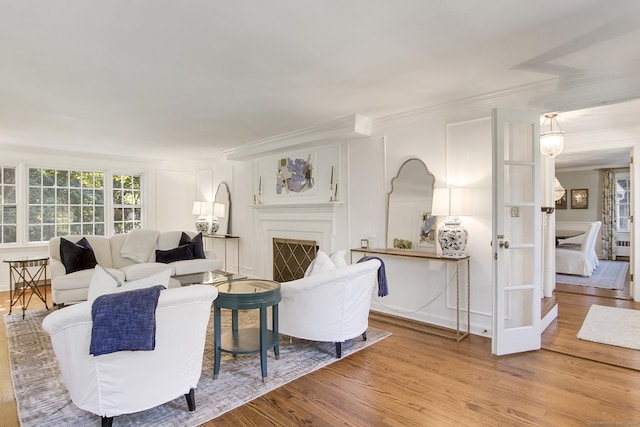 living room with a decorative wall, wood finished floors, a fireplace, and ornamental molding