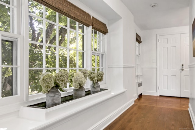 corridor with radiator, dark wood-type flooring, and baseboards