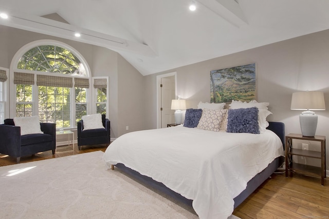 bedroom with wood finished floors and high vaulted ceiling