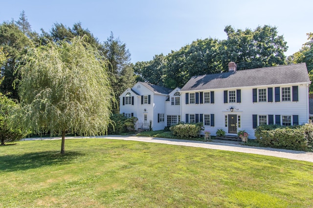 colonial home with a front yard and a chimney