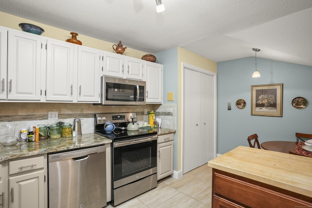 kitchen with tasteful backsplash, hanging light fixtures, white cabinets, and appliances with stainless steel finishes