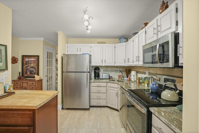 kitchen with a sink, stainless steel appliances, tasteful backsplash, and white cabinets